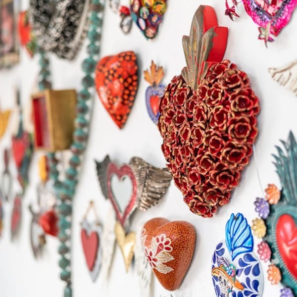 A wall adorned with various colorful heart-shaped Mexican folk art decorations.